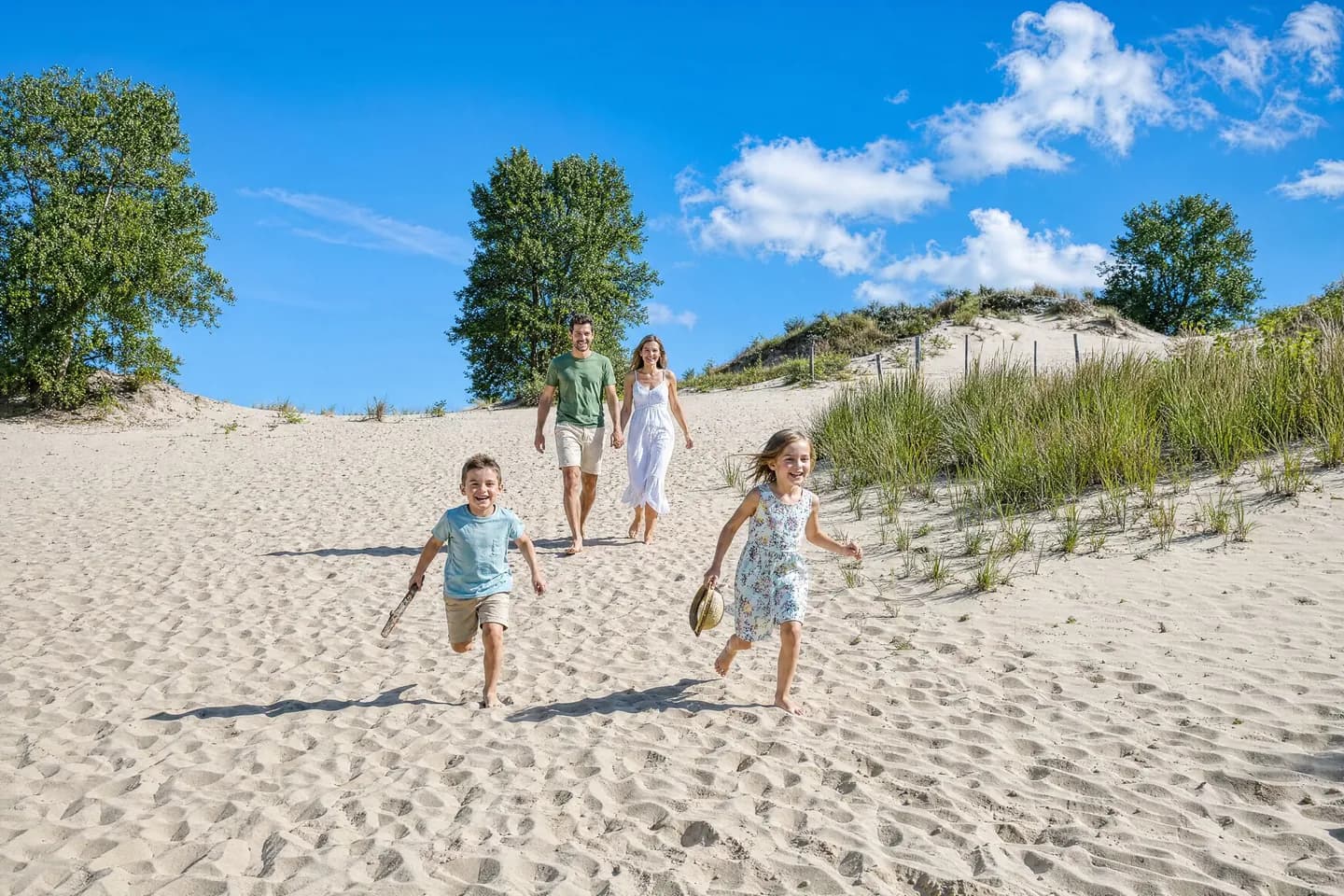 Kinderen lopen door het duinzand naar het strand